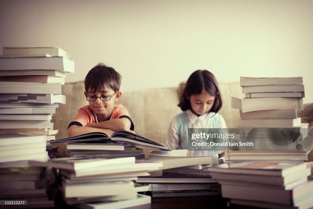 Josh and his sister as kids, reading at a table piled high with books
