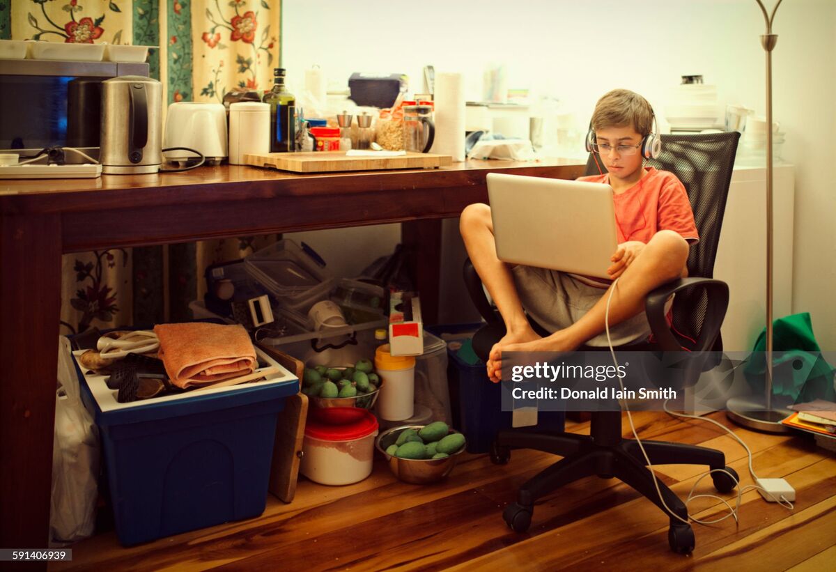 Josh in headphones with a laptop on his knees in a desk chair